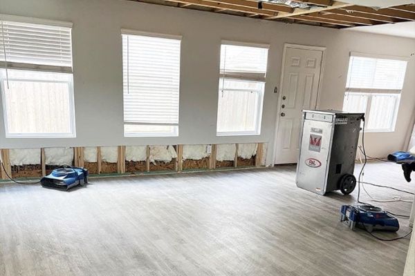 Milwaukee County room with drywall removed, exposed insulation, and drying fans after flood damage.