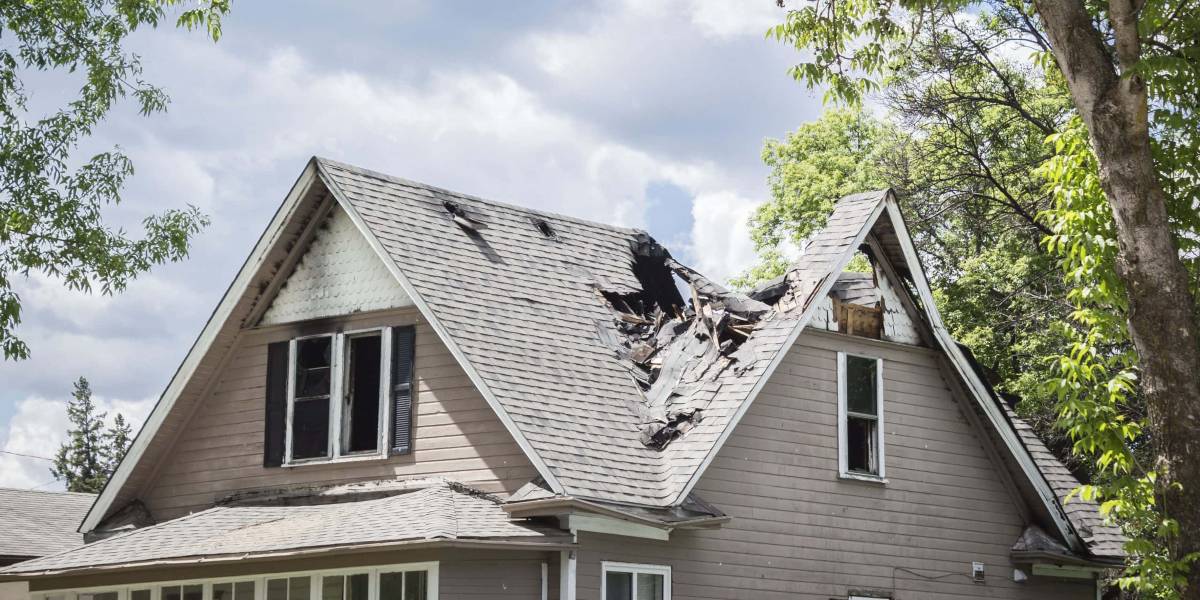 A house with a damaged roof and missing shingles in need of Flood Damage Restoration Milwaukee County.