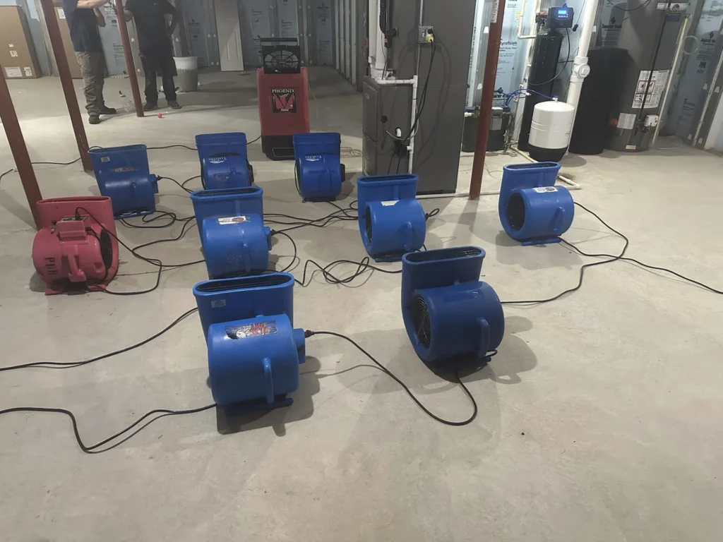 Air movers and dehumidifiers drying a concrete floor after water damage