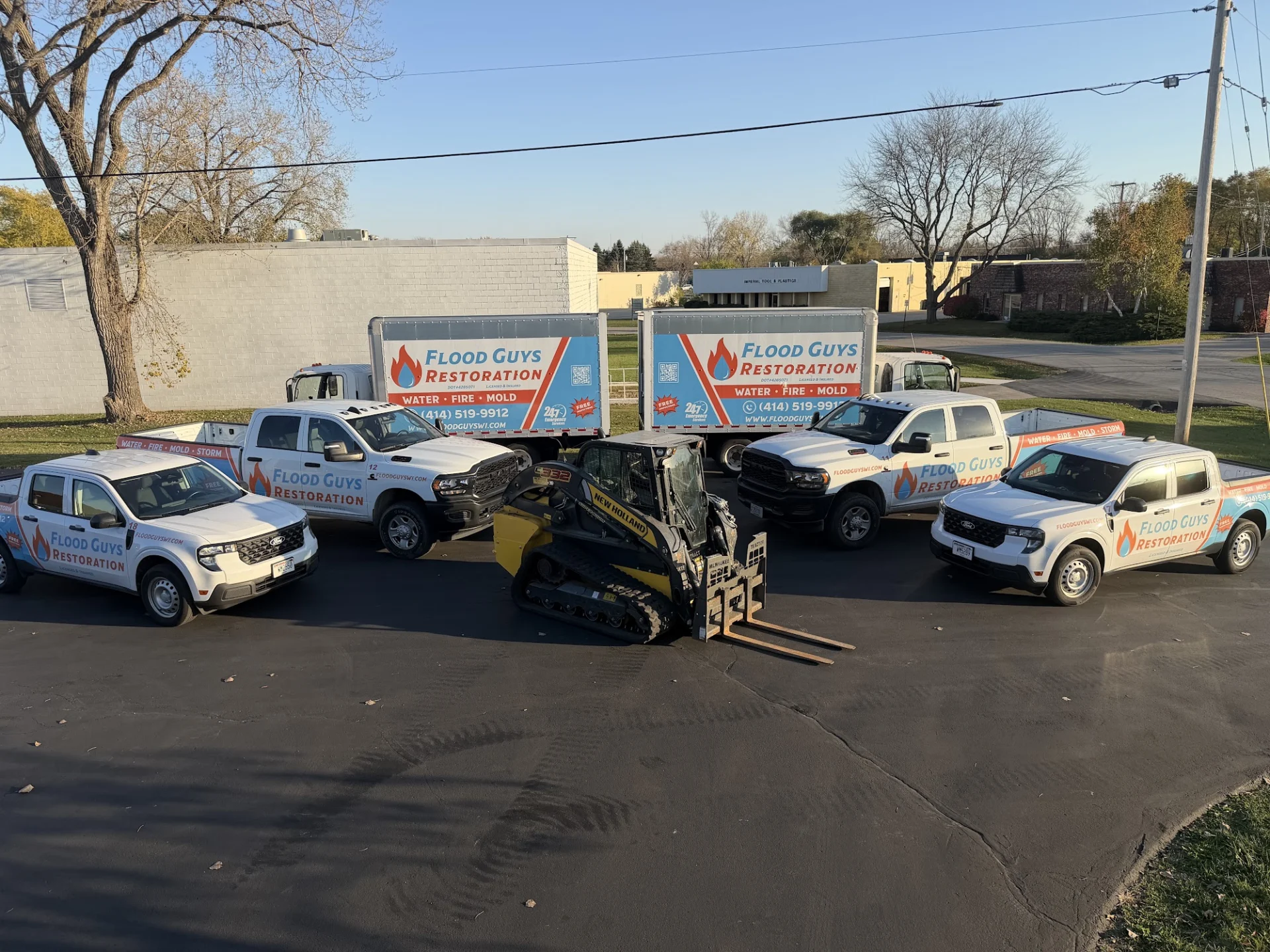 Flood Guys Restoration trucks and equipment trailers parked outside the shop in Greendale, WI