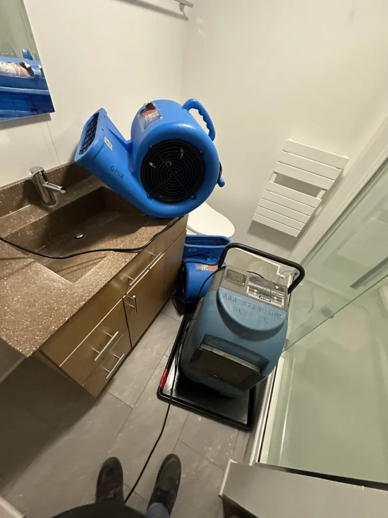 Air mover and dehumidifier drying kitchen cabinets and flooring after a leak