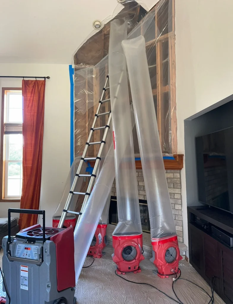 Plastic containment barrier with air scrubber ducting set up inside a home during restoration