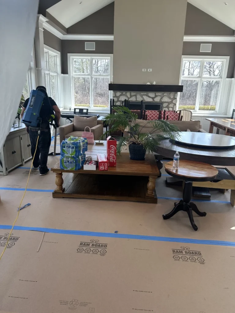 Technician using a backpack vacuum while cleaning a great room