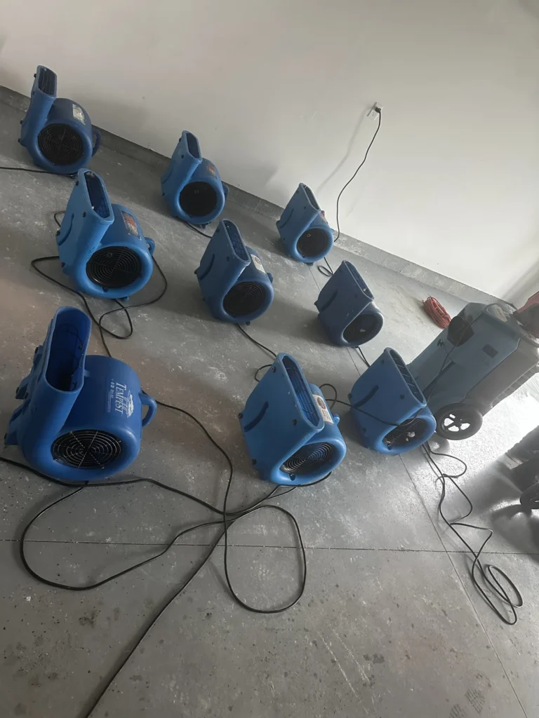 Air movers and a dehumidifier drying a room after water damage